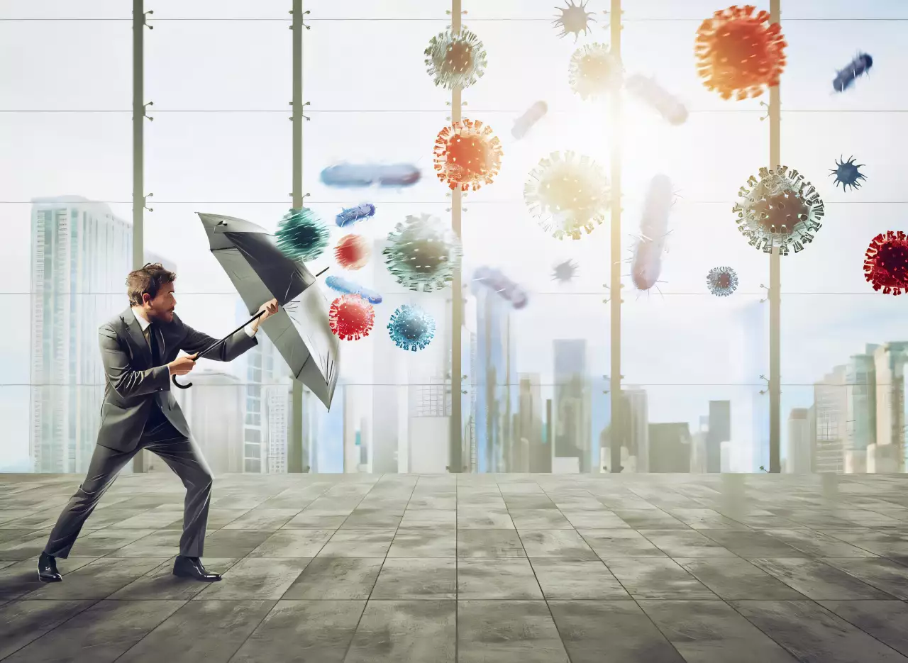 Homme d'affaires avec parapluie face à des virus, concept de protection financière.