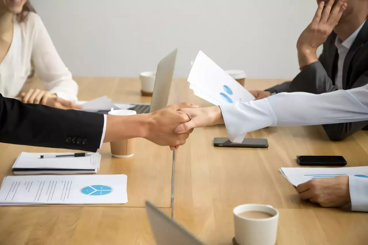 Poignée de main en réunion pour financement LBO, experts discutant stratégies d'entreprise.